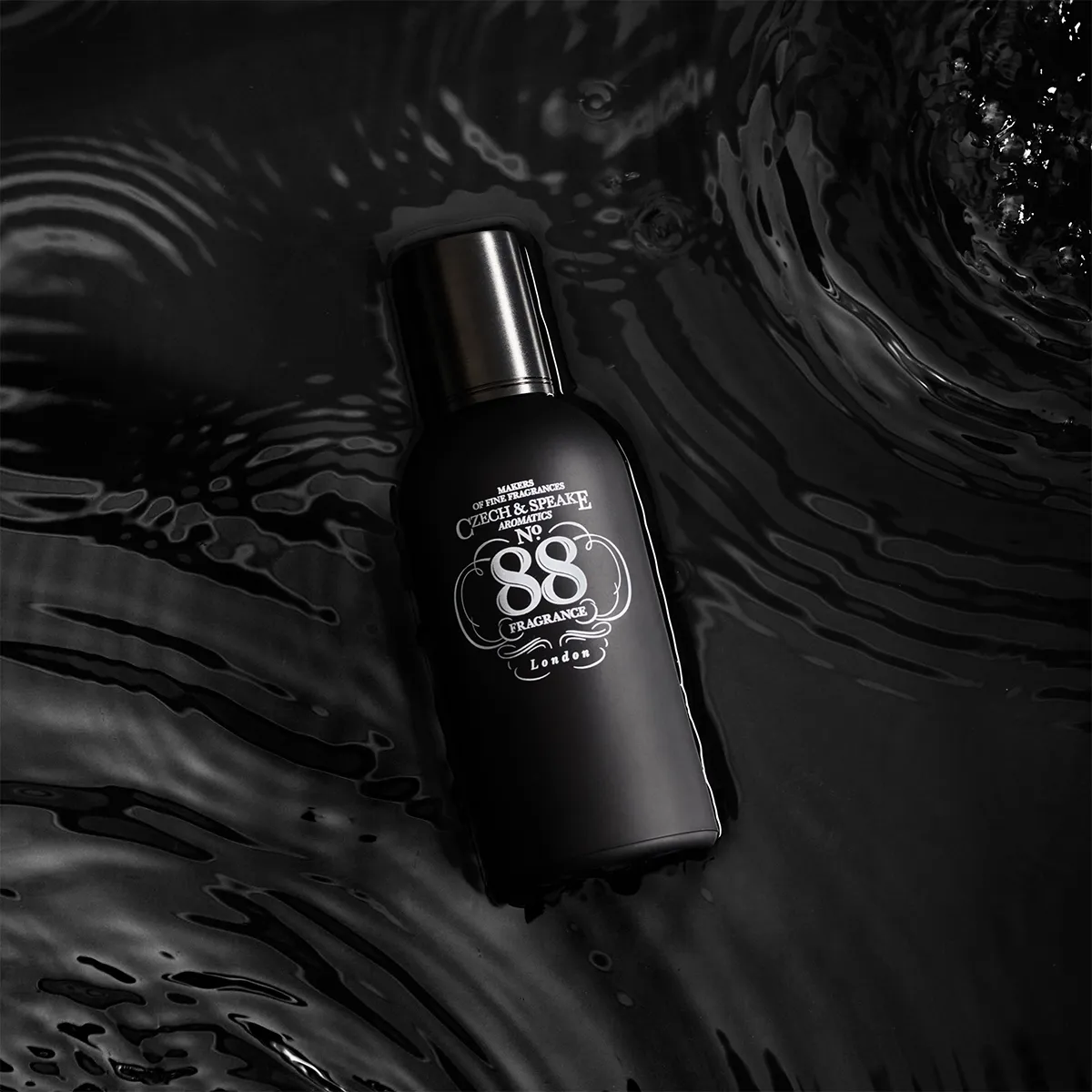 Black perfume bottle with '88 Fragrances' label on water
