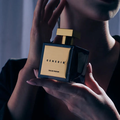 Person holding a black and gold 'Genesis' perfume bottle.