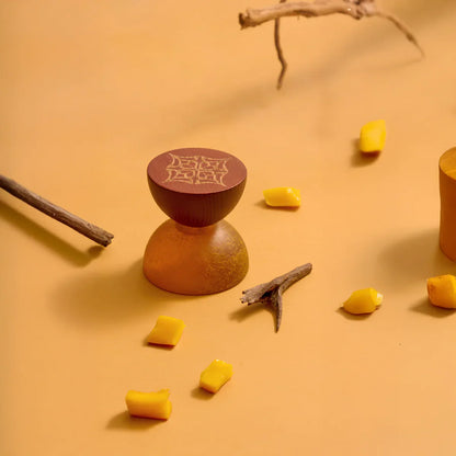 Mango Oud by LOVA perfume bottle styled with mango slices and wood on orange background
