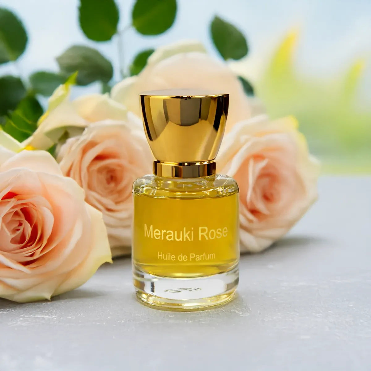 Merauki Rose perfume bottle surrounded by soft pink roses and fresh green leaves